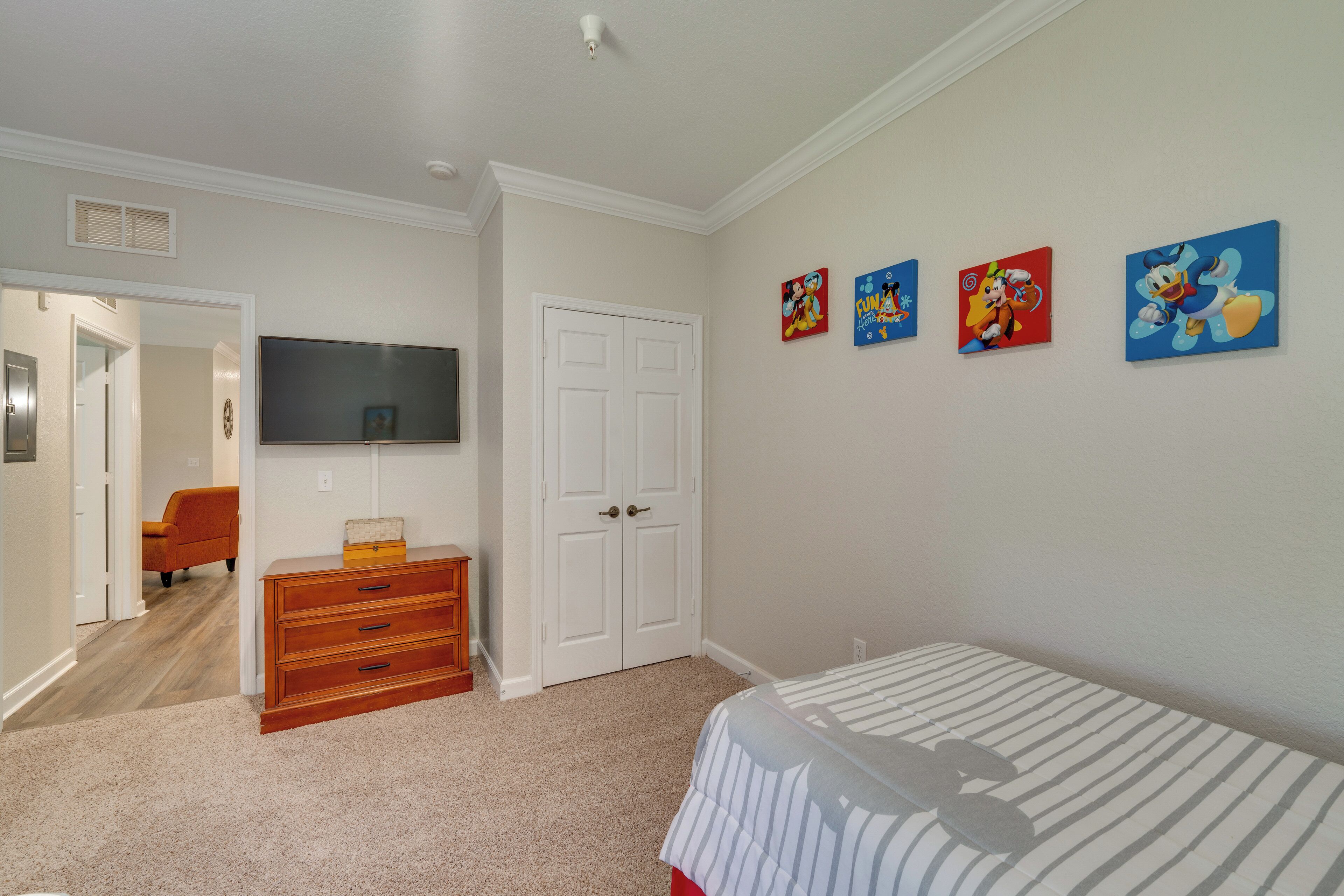A bedroom with a bed, a dresser, a TV, and a door.