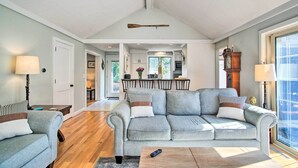 A spacious living room with a grey sofa, a coffee table, and a dining area in the background.