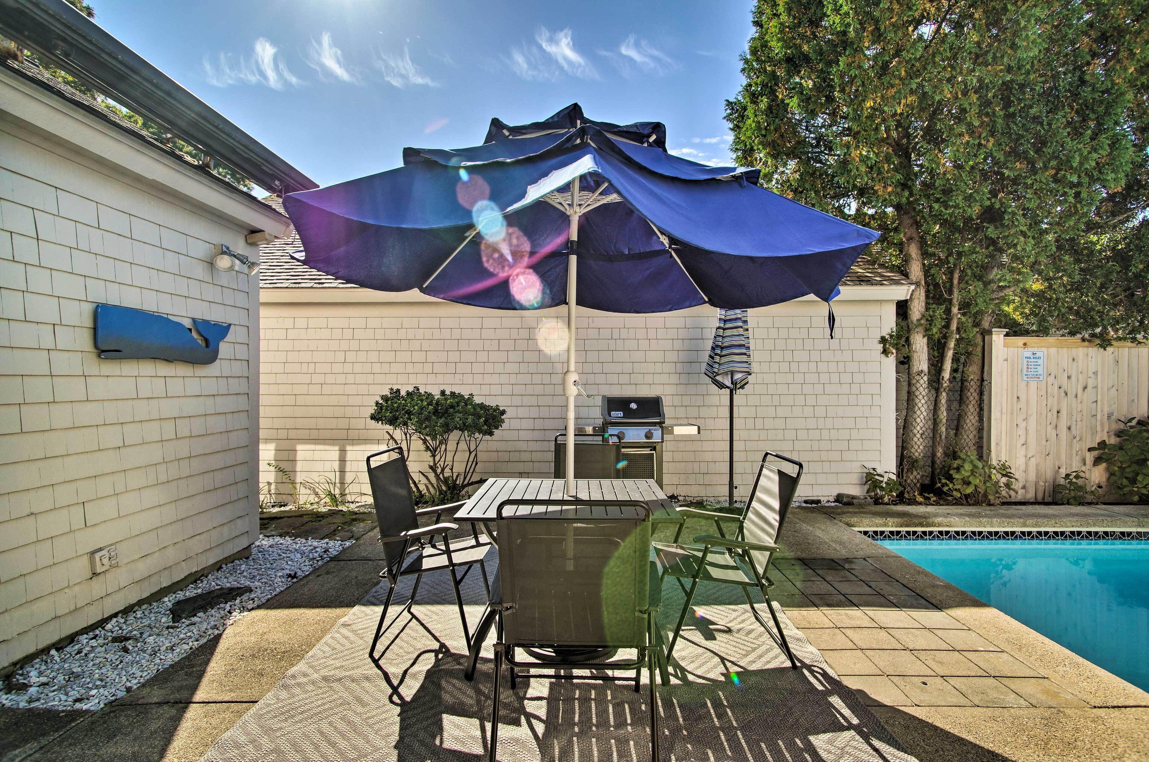 A backyard with a pool, patio furniture, and a barbecue grill.