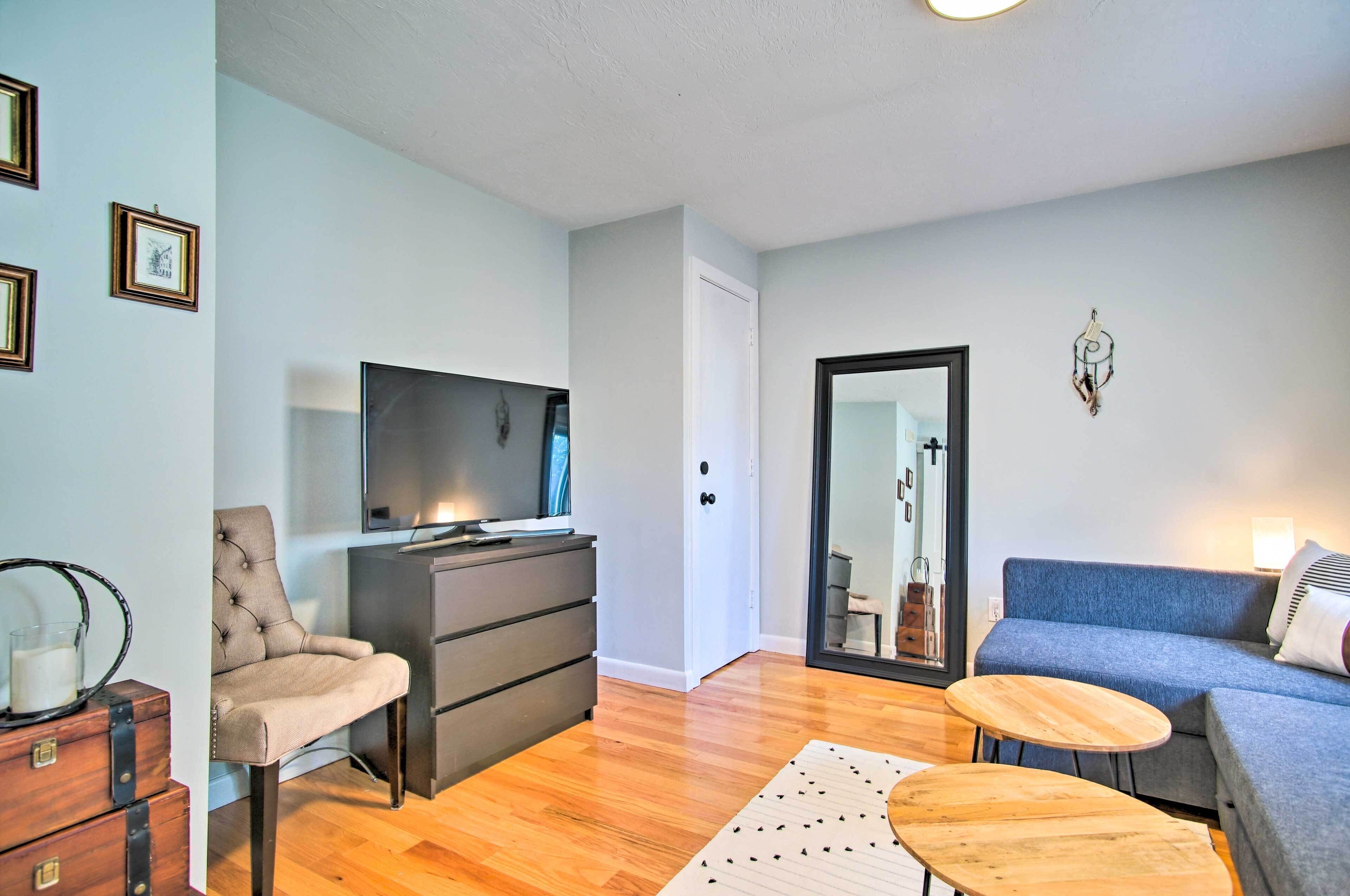 A living room with a sofa, a chair, a TV on a dresser, and a small wooden table.