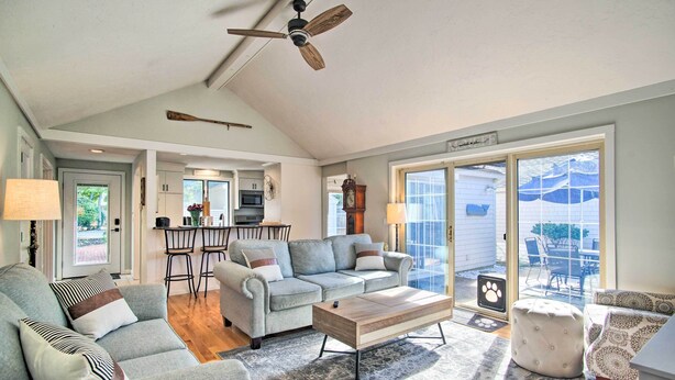 A spacious living room with a grey sofa, a wooden coffee table, and a ceiling fan.