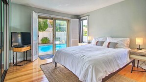 A bedroom with a large bed, a TV, and a sliding glass door leading to a pool.