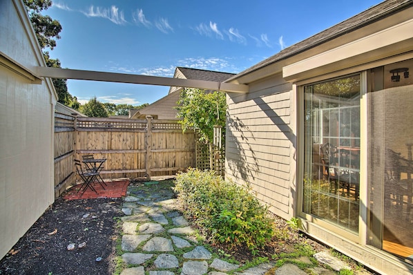 A backyard with a stone pathway, a wooden fence, and a patio with outdoor furniture.