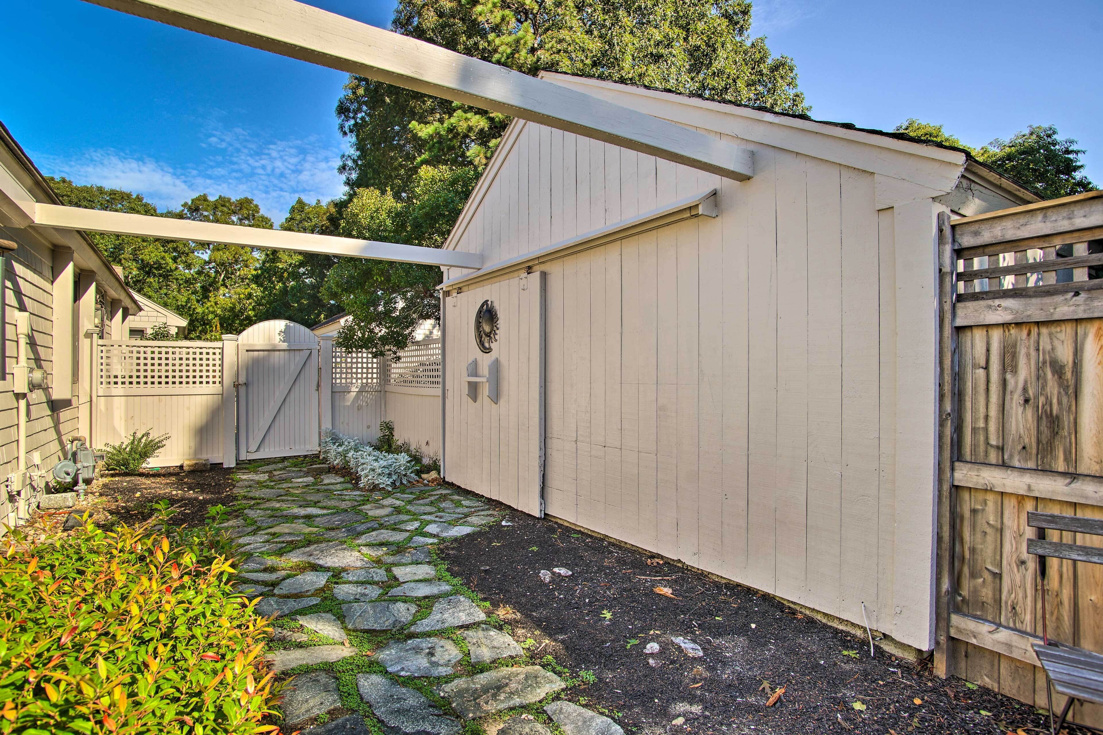 A covered patio area with a stone pathway leading to a wooden gate.