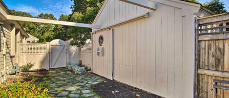 A covered patio area with a stone pathway leading to a wooden gate.