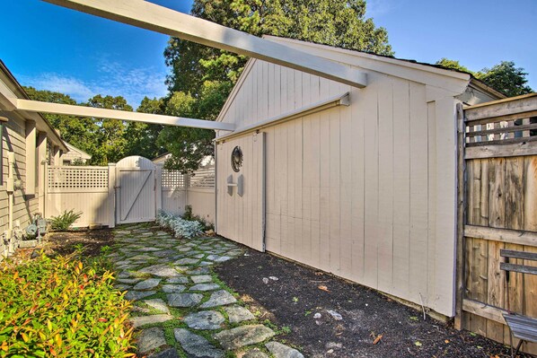 A covered patio area with a stone pathway leading to a wooden gate. - 2 Mi to Beach: Retreat w/ Pool & Grill in Mashpee! (Mashpee)
