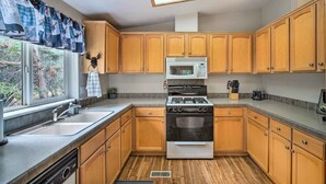 Une cuisine avec des meubles de rangement en bois, un four à micro-ondes, une cuisinière et un évier.