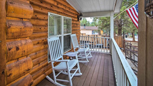 Une cabane en bois dotée d’un porche avec des fauteuils à bascule et une table.