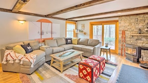 Una sala de estar acogedora con un sofá modular, una mesa de centro de madera y una chimenea de piedra.