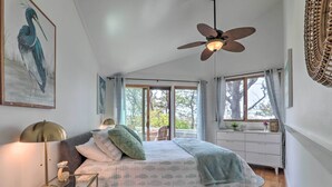 A bedroom with a bed, a standing lamp, a ceiling fan, and a window with curtains. - Private Ocean Overlook! Serene Cape Cod Escape (Mashpee)