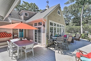 A covered patio with a table and chairs, surrounded by potted plants and a wooden deck. - Cape Cod Cottage w/ Deck, Grill, & Games! (Falmouth)
