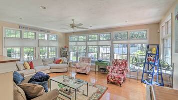 A spacious living room with a beige sofa, a red floral armchair, and a glass coffee table.