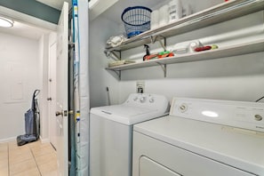A laundry area with a washing machine and dryer, shelves with cleaning supplies, and a vacuum cleaner. - West Yarmouth Home w/ Deck < 2 Mi to Beach! (West Yarmouth)