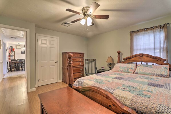 A bedroom with a wooden bed, a ceiling fan, a window with curtains, and a wooden dresser. - West Yarmouth Home w/ Deck < 2 Mi to Beach! (West Yarmouth)