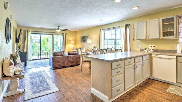 A spacious kitchen with a central island, a dining area with a table and chairs, and a living room with a sofa and chairs.