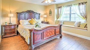 A bedroom with a large bed, nightstands, a ceiling fan, a window with curtains, and a built-in bench with cushions.