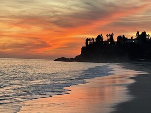 A beach with a sunset, calm sea, and a rocky cliff with trees. - Urb. Jardines de Burriana, 1 bed Ground floor, step free - PRIVATE PARKING (Nerja)