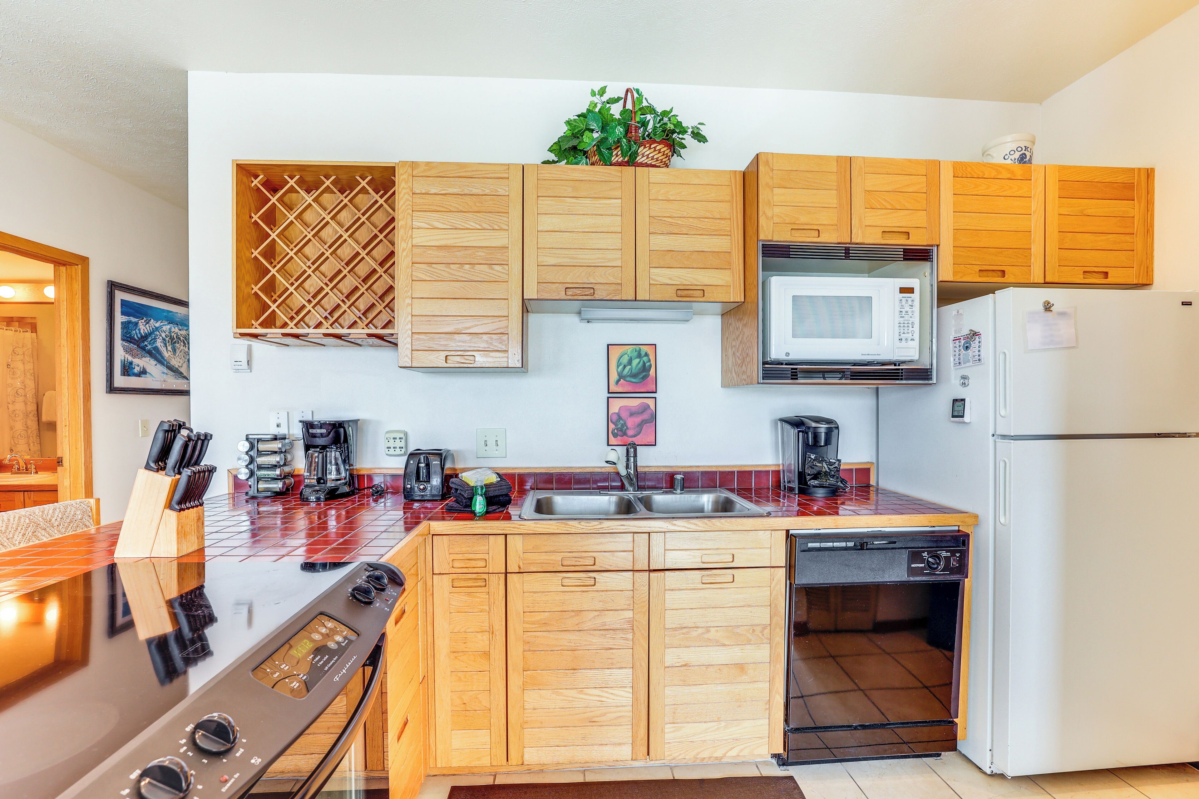 A modern kitchen with wooden cabinets, a stainless steel stove, a microwave, and a refrigerator.