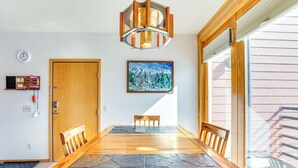 A dining area with a wooden table and chairs, a clock, a painting, and a door.