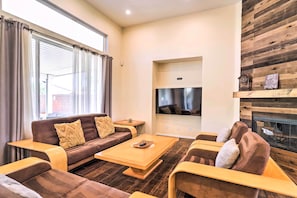 Ein modernes Wohnzimmer mit einem braunen Sofa, einem Couchtisch aus Holz und einem an einer Holzwand montierten Flachbildfernseher.