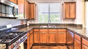 A kitchen with wooden cabinets, a stainless steel stove, and a granite countertop. - Welcoming Coachella Home w/ Heated Salt Pool! (Coachella)