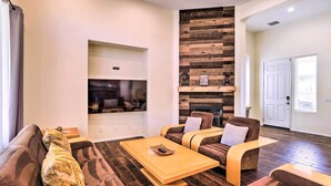 A modern living room with a fireplace, comfortable seating, and a flat-screen TV mounted on the wall. - Welcoming Coachella Home w/ Heated Salt Pool! (Coachella)