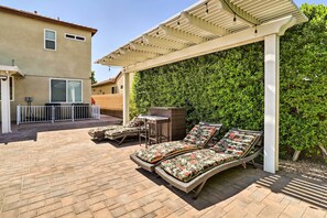 Eine Terrassenfläche mit zwei Korbsesseln und einem kleinen Tisch, umgeben von einem Pflasterboden und einer Pergola.
