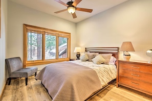 Une chambre à coucher comprenant un lit, une chaise, une table de chevet avec une lampe, une commode et un ventilateur de plafond.