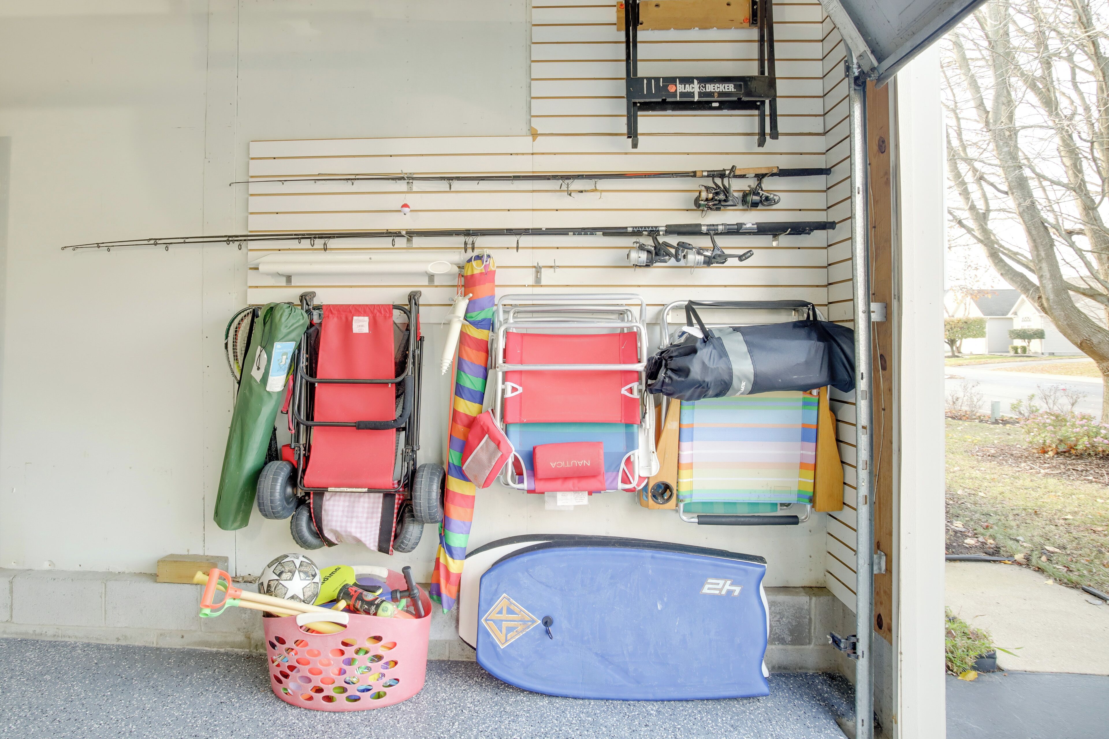 A garage with various items including a blue boat, life jackets, and a colorful striped bag.