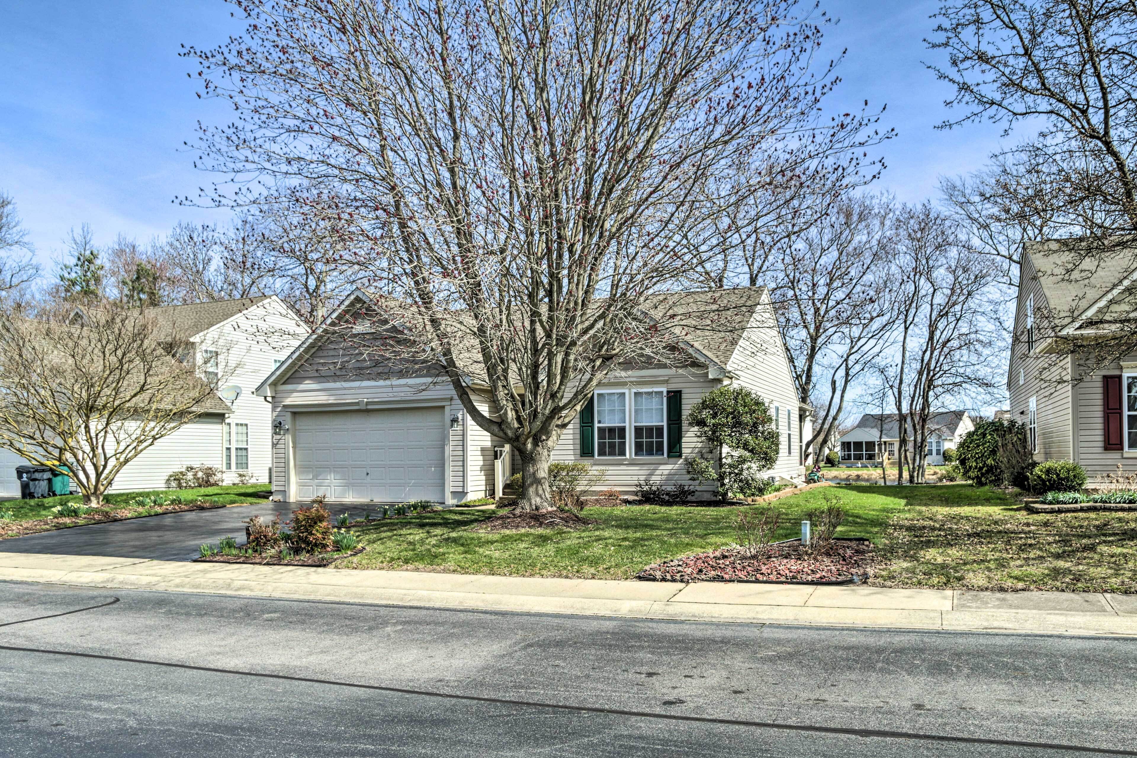 A suburban residential area with detached houses, a clear sky, and a well-maintained lawn.