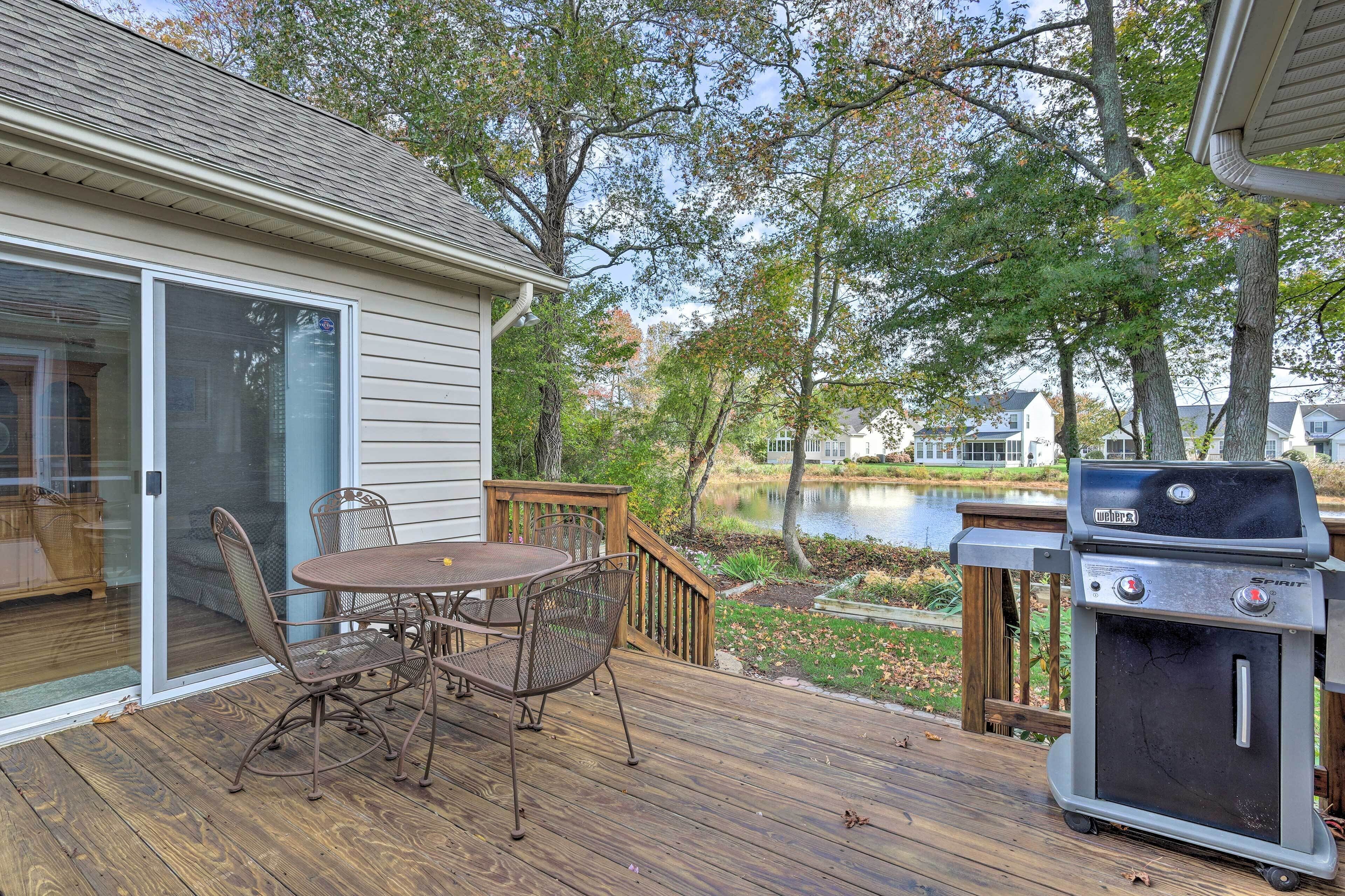 A deck with a grill, a table, and chairs.