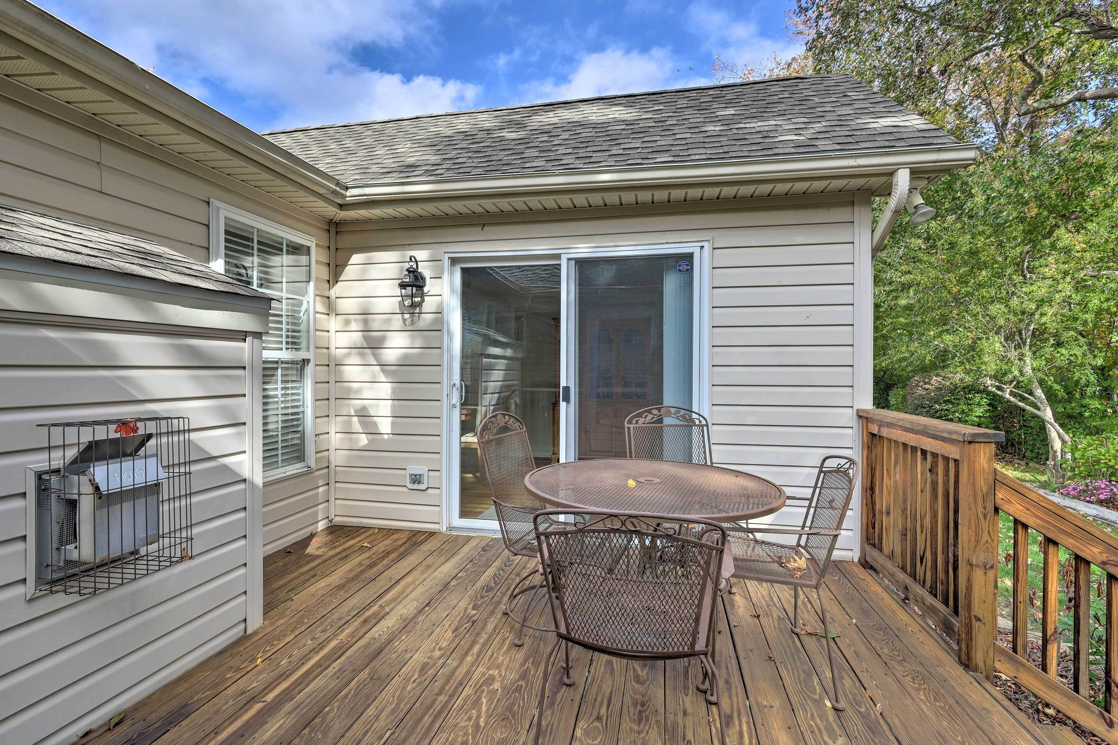 A covered patio with a table and chairs, a sliding glass door, and a wooden deck.