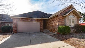 A two-story house with a brick facade, a large garage door, and a small front porch. - Deer Valley 164 (Branson)