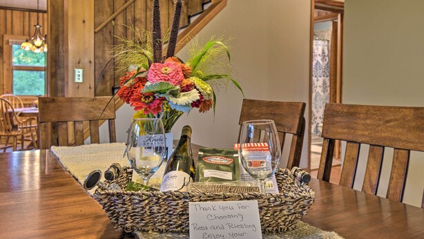 A dining table with a basket containing a bottle, a glass, and a note.