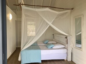A bedroom with a canopy bed, a bedside table, and a mirror. - Villa Coco Câline, 2 suites, infinity pool (Capesterre-de-Marie-Galante)