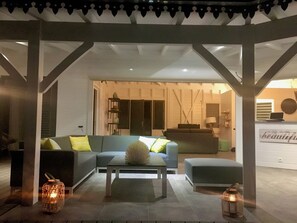 A modern living room with a sofa, a coffee table, and two side tables. There is a bookshelf and a lamp in the background. - Villa Coco Câline, 2 suites, infinity pool (Capesterre-de-Marie-Galante)