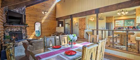 A cozy log cabin interior with a dining area, fireplace, and kitchen.