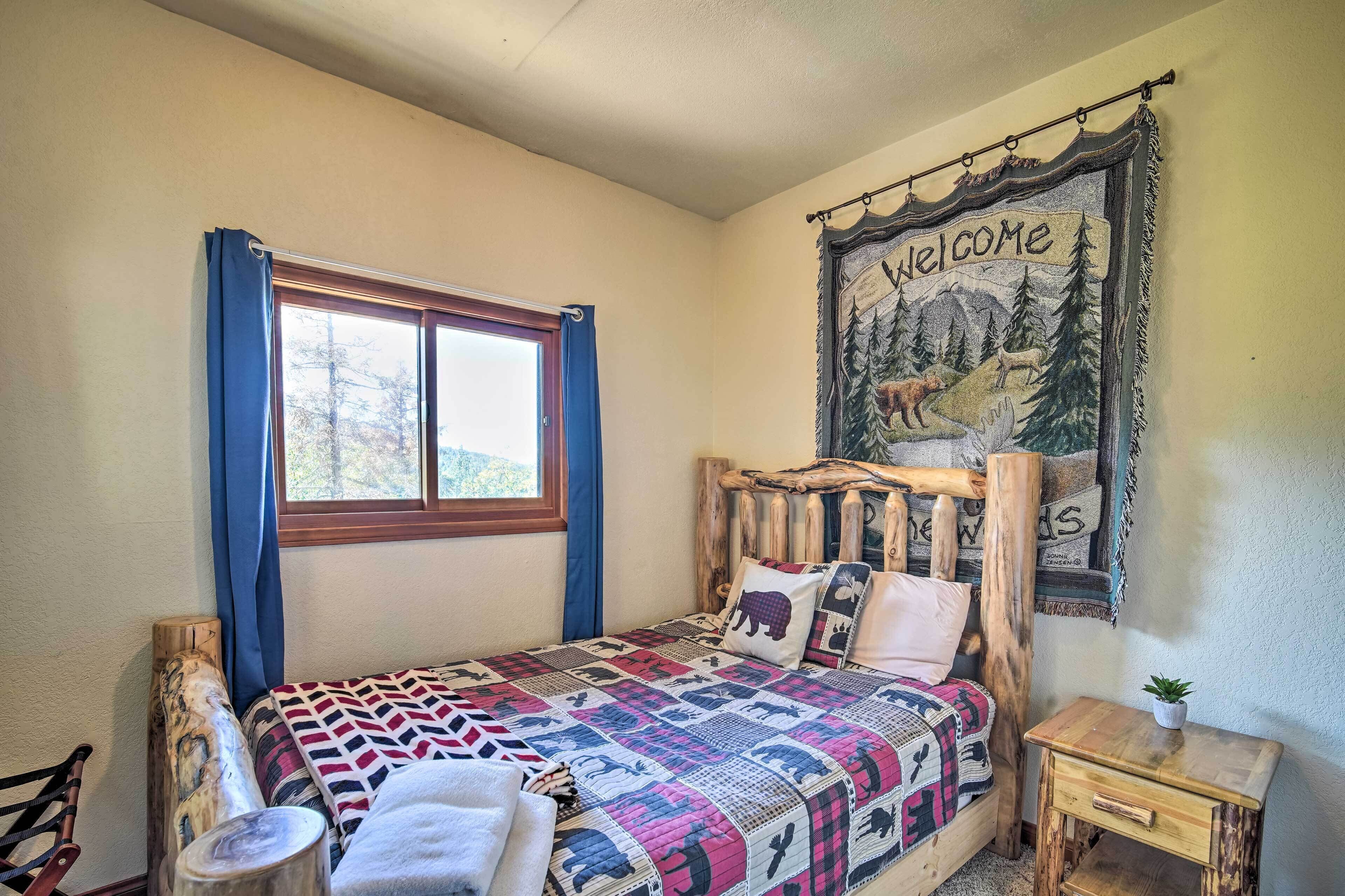 A bedroom with a wooden headboard, a quilted bedspread, a welcome tapestry, and a small bedside table.
