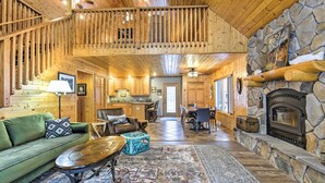 A spacious log cabin interior with a dining area, kitchen, and a stone fireplace. - Crandon Cabin Getaway w/ Boat Dock & Deck! (Crandon)