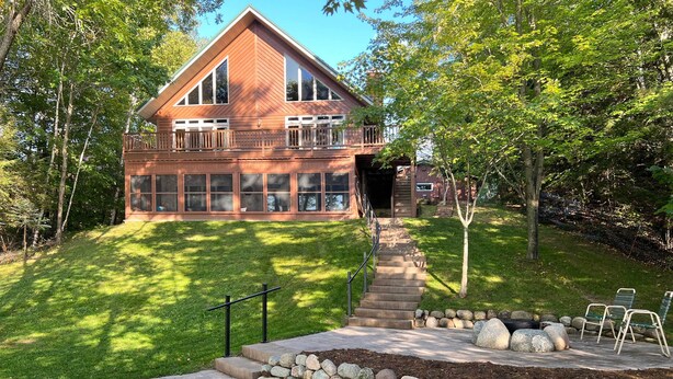 A two-story wooden house with a large deck and a stone staircase leading to a covered entryway. - Crandon Cabin Getaway w/ Boat Dock & Deck! (Crandon)