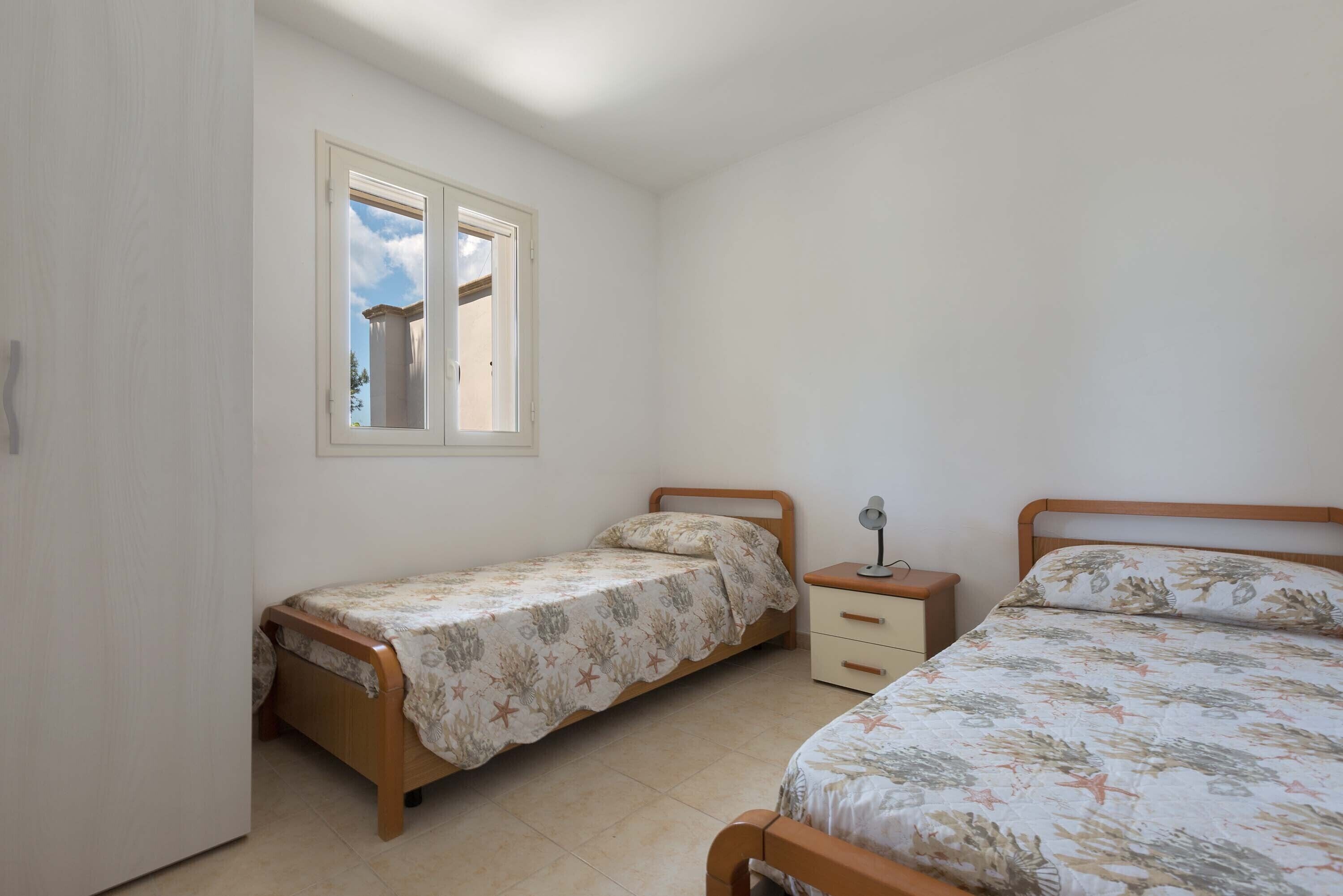 Ein Schlafzimmer mit zwei Einzelbetten, einem Fenster und einem Nachttisch mit Lampe.