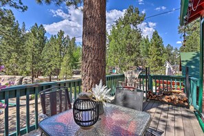 A wooden deck with a table and chairs, surrounded by trees and a green railing. - Big Bear Cabin Close to Lake, Trails & Village! (Big Bear Lake)