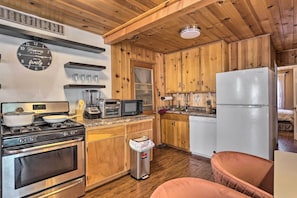 A kitchen with wooden cabinets, a stove, a microwave, and a refrigerator. - Big Bear Cabin Close to Lake, Trails & Village! (Big Bear Lake)