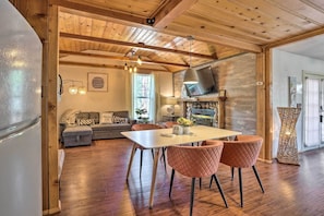 A modern kitchen with a built-in oven, a dining area with a white table and two chairs, and a cozy living room with a sofa and a TV. - Big Bear Cabin Close to Lake, Trails & Village! (Big Bear Lake)