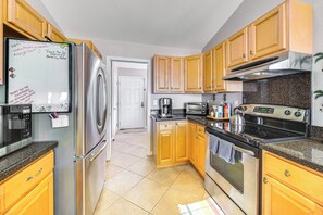 A kitchen with wooden cabinets, stainless steel appliances, and a whiteboard with messages.