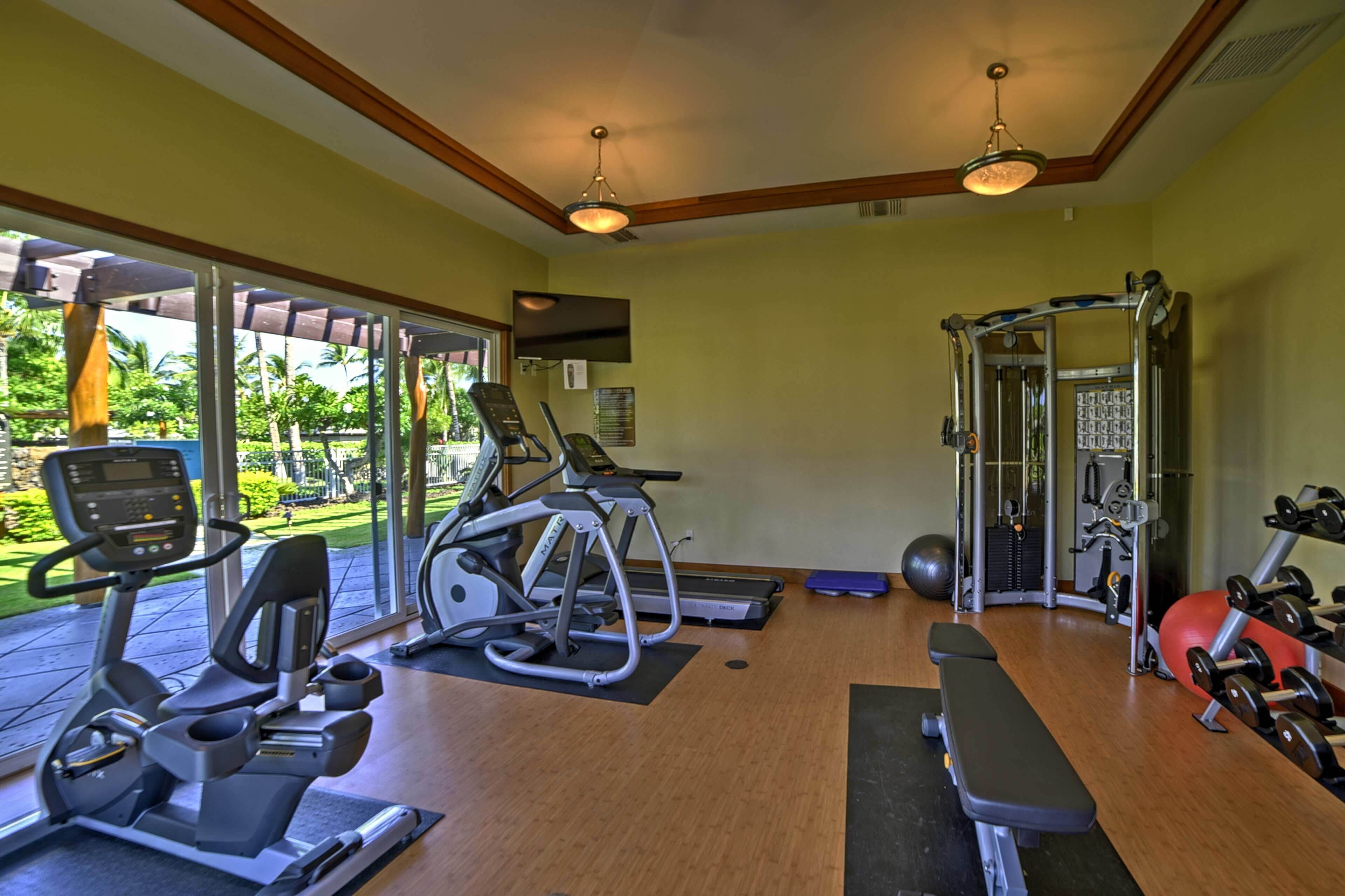 Un gimnasio con máquinas de cardio, una banca y equipo de levantamiento de pesas.