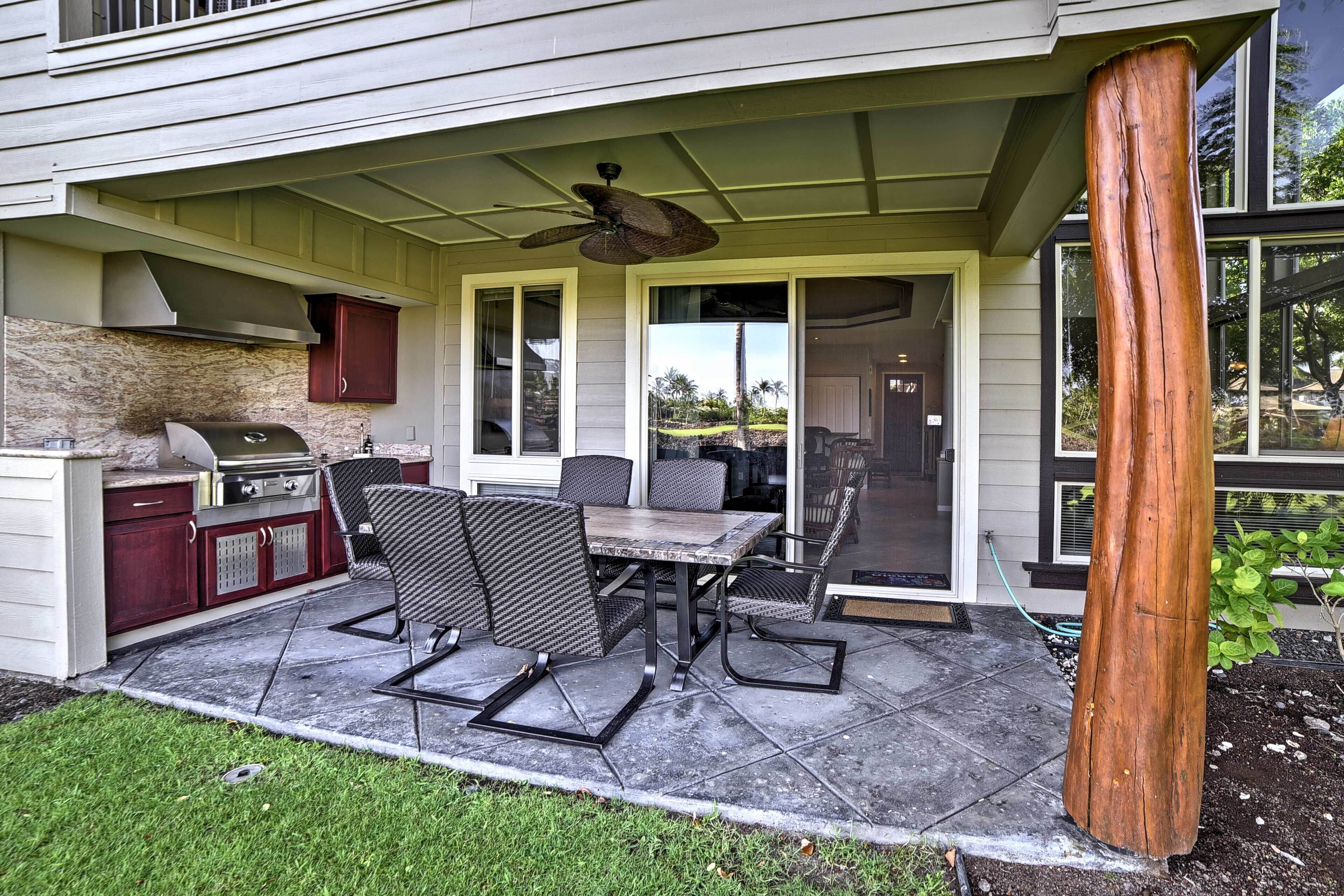 An outdoor patio with a grill, dining table, and chairs.