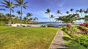 A tropical resort with a grassy lawn, palm trees, and a beach view. - Luxury Mauna Lani Resort Villa - Beach Access! (Kamuela)