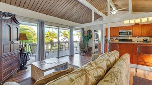A spacious living area with a wooden ceiling, a sofa, a dining table, and a kitchen with a microwave.