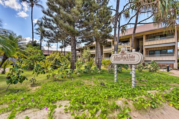 Señalización de 'Kihei Bay Vista' mostrando una vista de un edificio y follaje circundante.